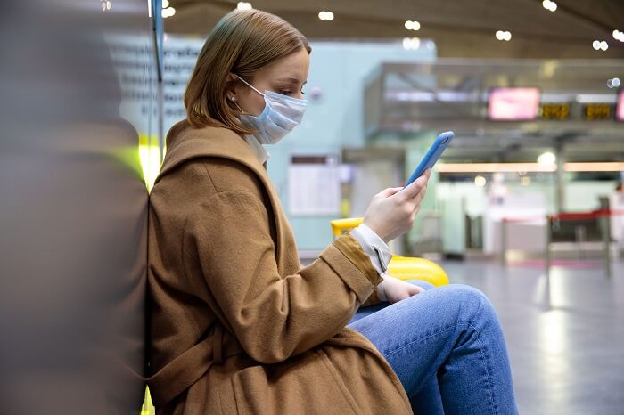 Mulher sentada em aeroporto mexendo em celular