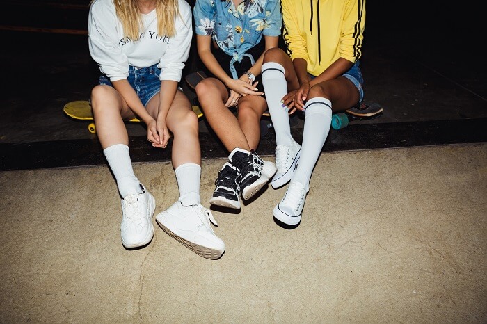 Três mulheres sentadas em skate usando look streetwear