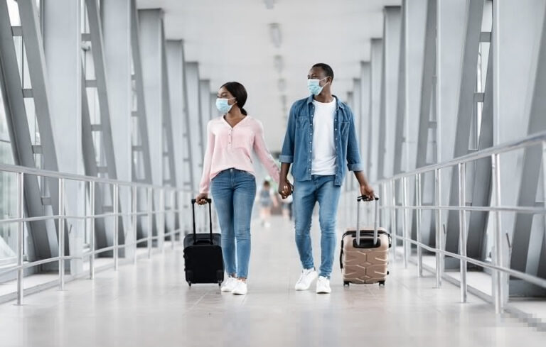 casal indo viajar em um aeroporto carregando duas malas